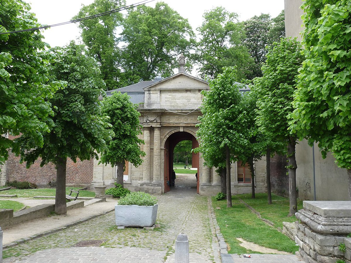 Le porche d'entrée de l'abbaye de Forest, entre les arbres.